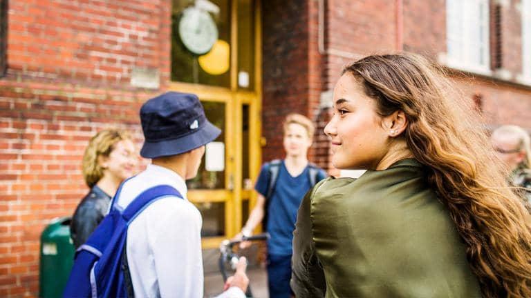 A group of young people outside the entrance to a building