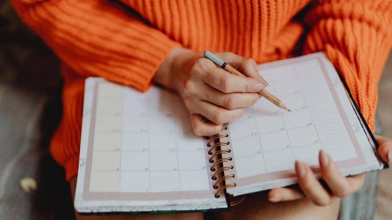  A woman holding an open diary and a pencil
